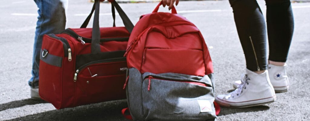 Two travelers holding red bags on a street, symbolizing travel and exploration.